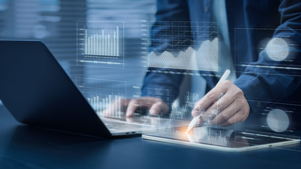 A stock image showing: Businessman uses computer with pen. Financial graph analysis concepts Stock market information. Reporting and Statistics Including KPI analysis on a blue background.